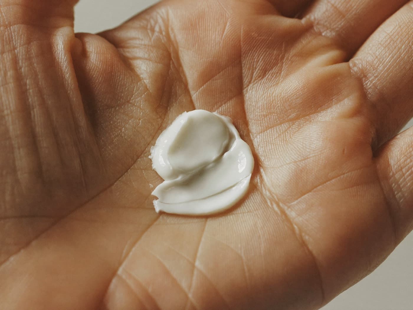 A small amount of white face cream in the palm of a hand