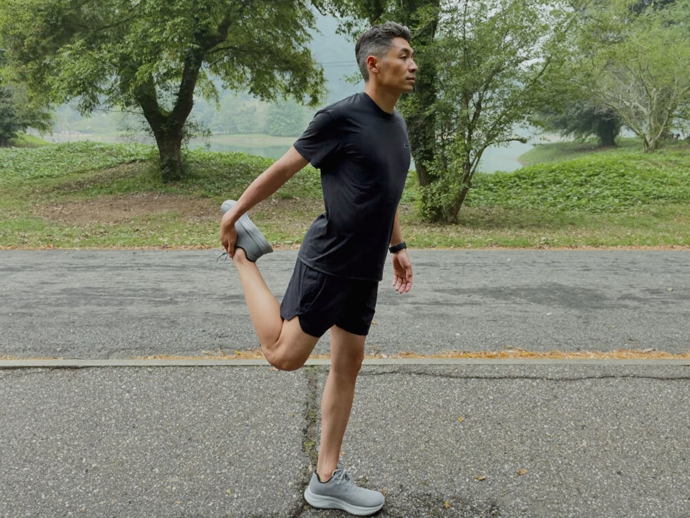 A man in his forties stretching after a morning run on a park path
