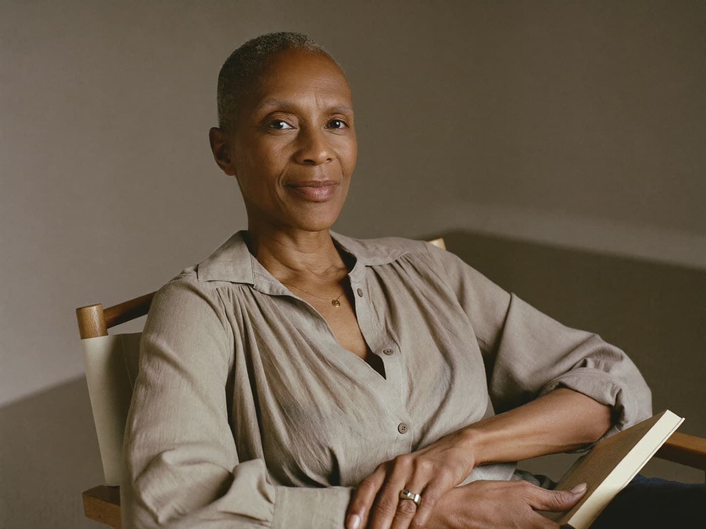 A woman in her fifties with short gray hair smiling in a sunlit reading chair